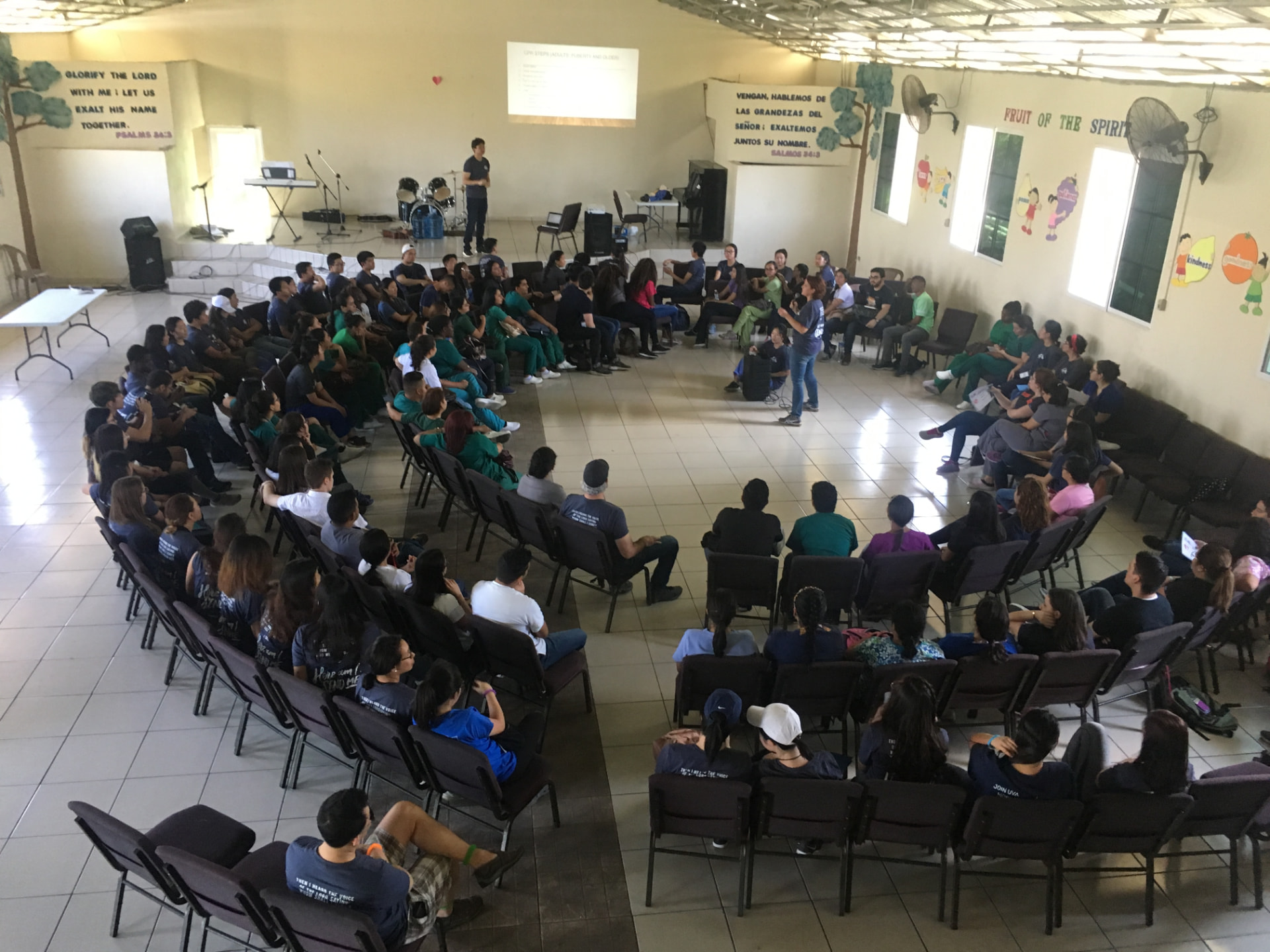 An experienced Christian healthcare mentor in conversation and prayer with a diverse group of young medical professionals around an open Bible